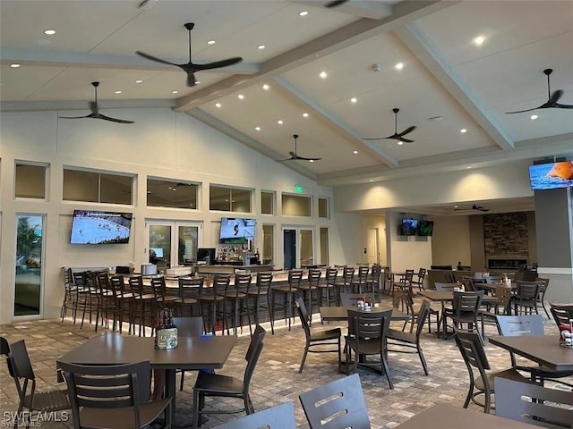 dining space with a ceiling fan, high vaulted ceiling, and beam ceiling