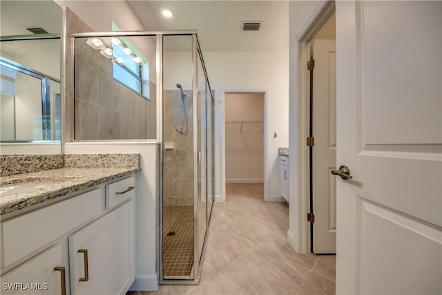 full bathroom with a walk in closet, tile patterned flooring, vanity, visible vents, and a stall shower