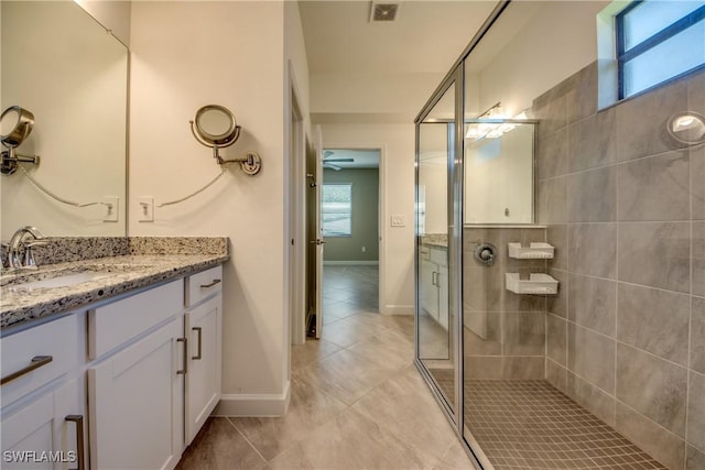 full bath featuring tile patterned flooring, vanity, baseboards, a shower stall, and visible vents