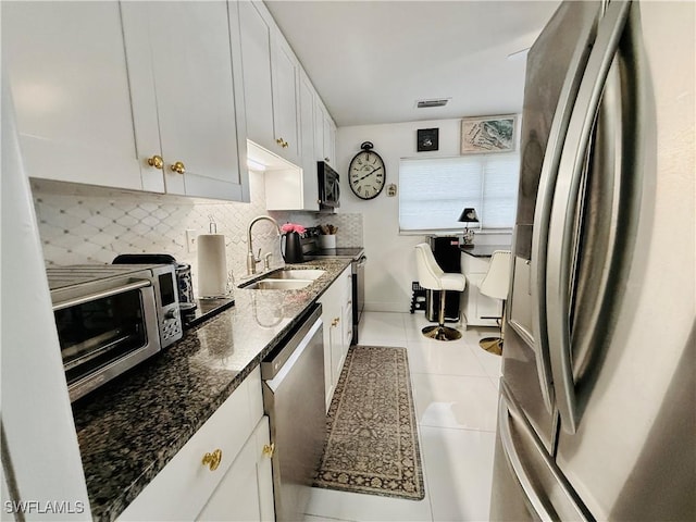 kitchen featuring visible vents, tasteful backsplash, a sink, appliances with stainless steel finishes, and light tile patterned floors