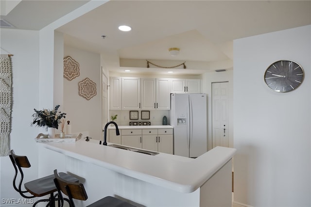 2743 1st St Unit 2001, Fort Myers, FL 33916 - kitchen with a breakfast bar area, a sink, white cabinets, a peninsula, and white fridge with ice dispenser
