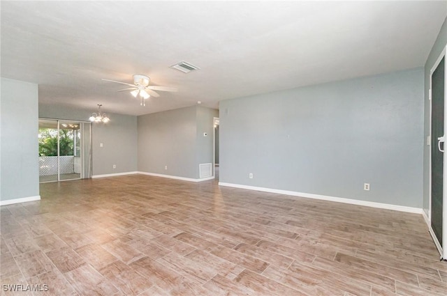 empty room featuring light wood-style floors, visible vents, baseboards, and ceiling fan with notable chandelier