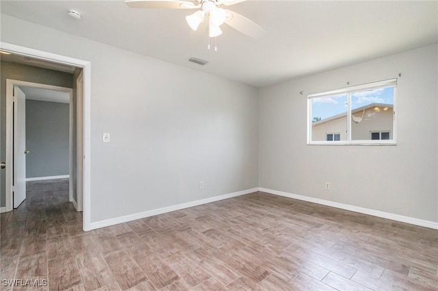 spare room with baseboards, wood finished floors, a ceiling fan, and visible vents