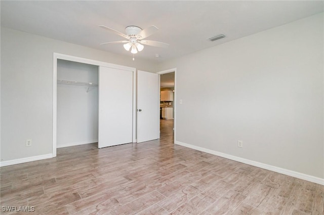 unfurnished bedroom with a closet, baseboards, visible vents, and light wood-style floors