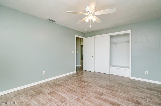 unfurnished bedroom featuring a closet, wood finished floors, visible vents, ceiling fan, and baseboards