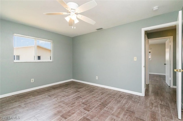 empty room with visible vents, wood finished floors, baseboards, and ceiling fan