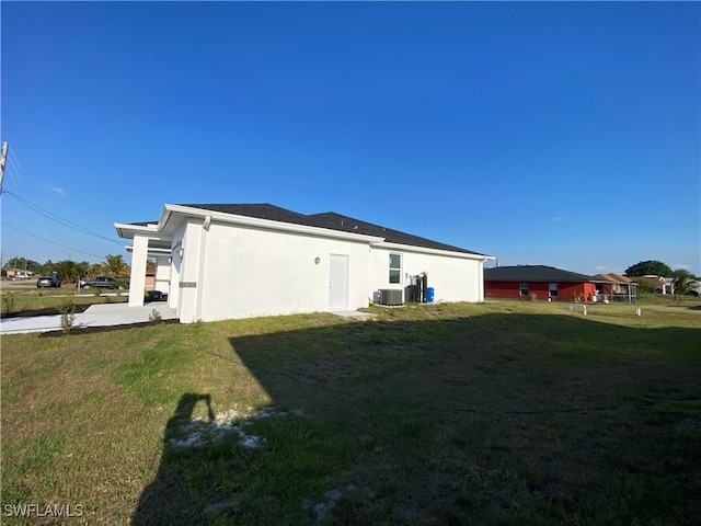 5249-5251 Centennial Blvd, Lehigh Acres, FL 33971 - view of home's exterior with stucco siding, a yard, and central AC