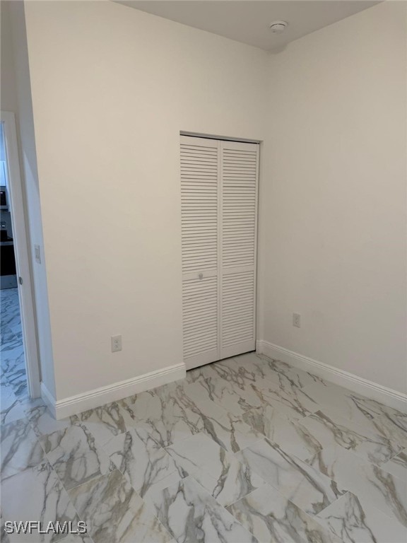 5249-5251 Centennial Blvd, Lehigh Acres, FL 33971 - unfurnished bedroom featuring light marble finish flooring, baseboards, and a closet