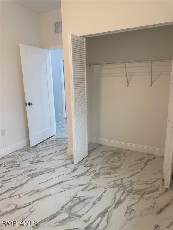 5249-5251 Centennial Blvd, Lehigh Acres, FL 33971 - unfurnished bedroom featuring a closet, marble finish floors, and baseboards