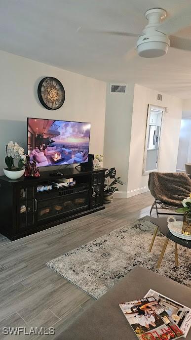 living area with baseboards, visible vents, and wood finished floors