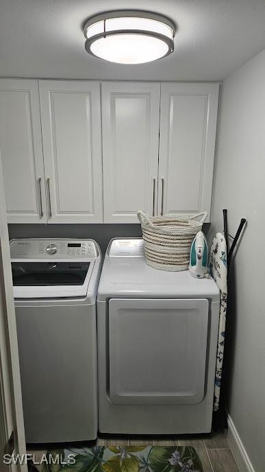 clothes washing area featuring baseboards, cabinet space, and washing machine and clothes dryer