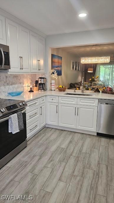 kitchen featuring light countertops, white cabinets, a sink, light wood-style flooring, and appliances with stainless steel finishes