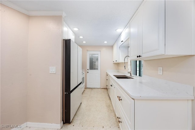 kitchen featuring a sink, light countertops, white cabinets, freestanding refrigerator, and recessed lighting
