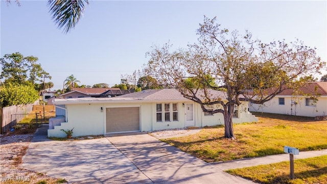 ranch-style house featuring an attached garage, stucco siding, fence, and driveway