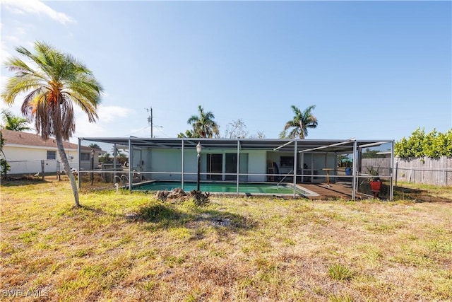 rear view of property featuring fence, a fenced in pool, a lawn, and a lanai