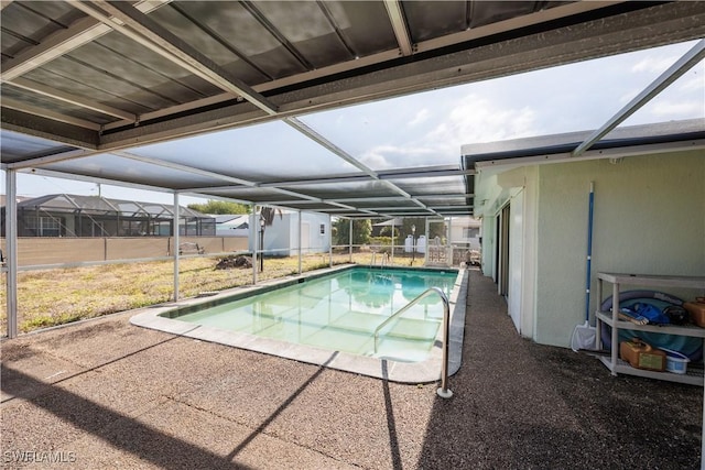 outdoor pool featuring a storage shed, an outbuilding, a patio area, and glass enclosure