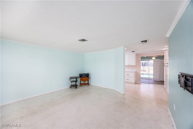 unfurnished room featuring crown molding, a textured ceiling, visible vents, and baseboards