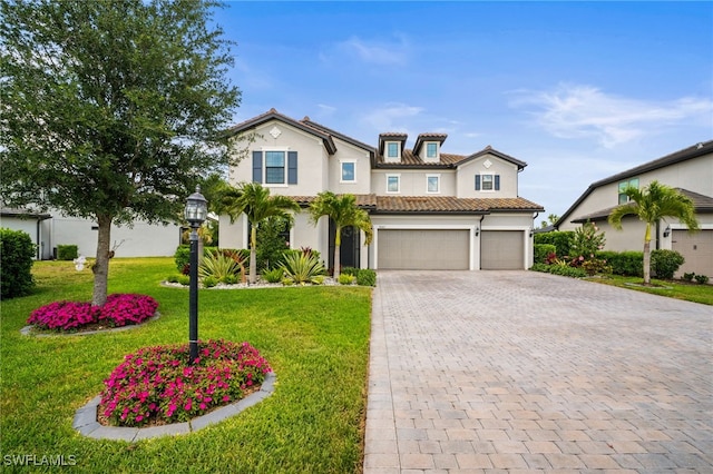 mediterranean / spanish-style home featuring a garage, a front yard, decorative driveway, stucco siding, and a tile roof