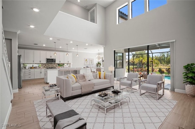 living room with a towering ceiling, baseboards, light wood-style floors, recessed lighting, and a notable chandelier