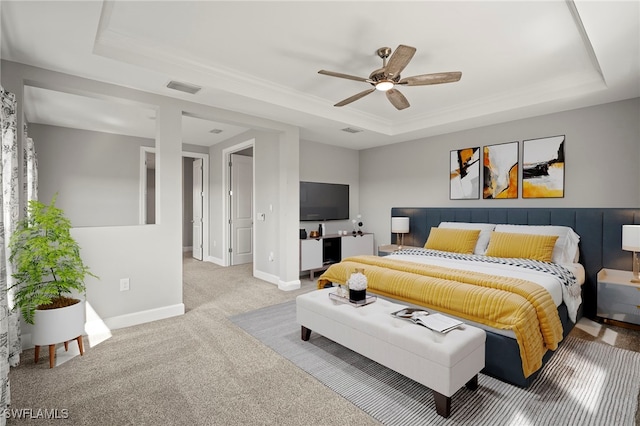 bedroom featuring visible vents, baseboards, a tray ceiling, a ceiling fan, and carpet
