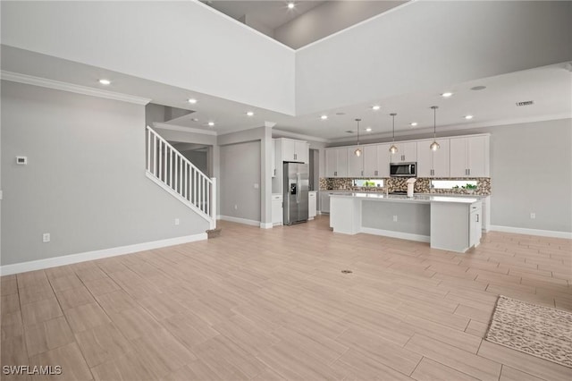 unfurnished living room featuring crown molding, stairway, baseboards, recessed lighting, and light wood-style flooring