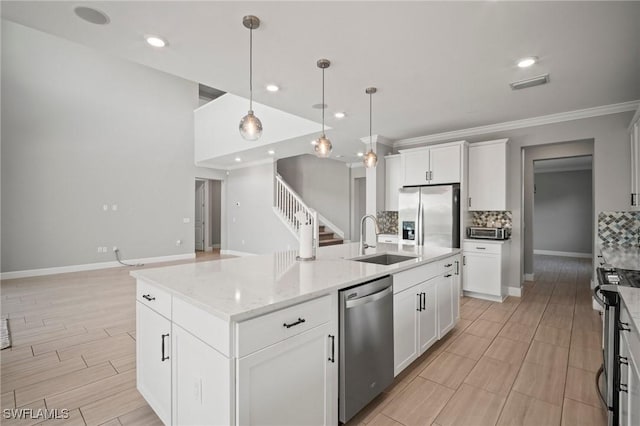 kitchen featuring a sink, stainless steel appliances, decorative light fixtures, backsplash, and visible vents