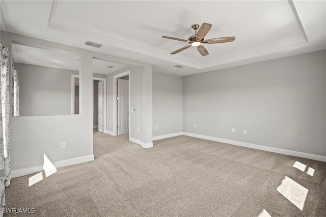 spare room with a ceiling fan, visible vents, carpet floors, baseboards, and a tray ceiling