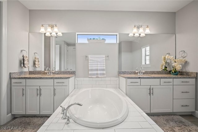 bathroom with a chandelier, two vanities, and a sink