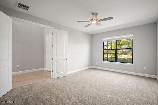carpeted empty room featuring ceiling fan, visible vents, and baseboards