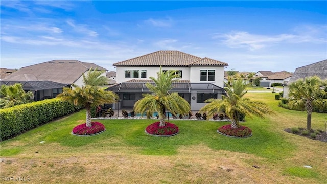 rear view of house featuring stucco siding, a tile roof, a lawn, a lanai, and a residential view