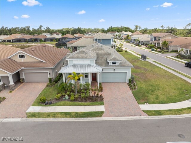 3419 Pilot Cir, Naples, FL 34120 - view of front of home featuring a front yard, decorative driveway, a residential view, an attached garage, and a tile roof