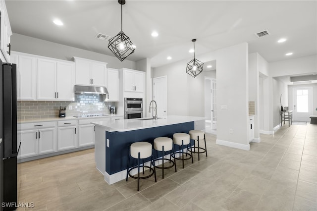 3419 Pilot Cir, Naples, FL 34120 - kitchen with visible vents, tasteful backsplash, black appliances, a breakfast bar, and under cabinet range hood