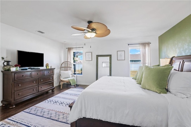 bedroom featuring visible vents, ceiling fan, dark wood-style flooring, and baseboards