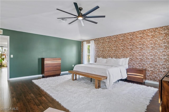 bedroom with lofted ceiling, baseboards, wood finished floors, and brick wall