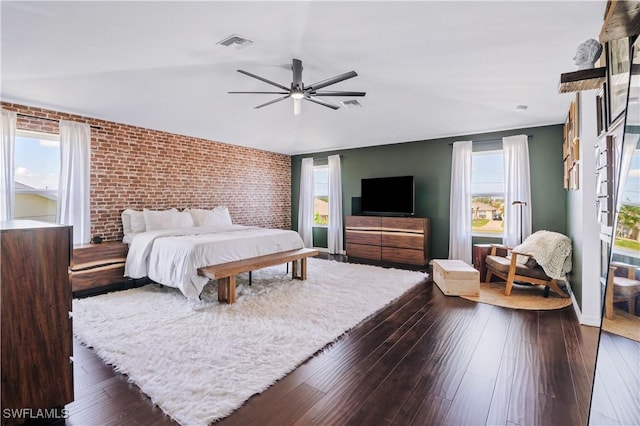 bedroom featuring visible vents, brick wall, and dark wood finished floors