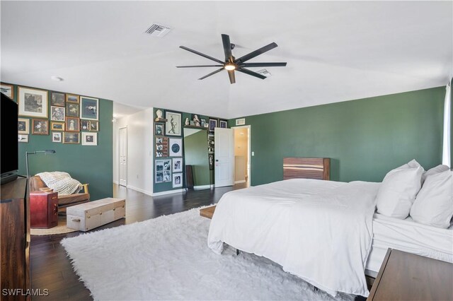 bedroom with ceiling fan, visible vents, vaulted ceiling, baseboards, and wood finished floors