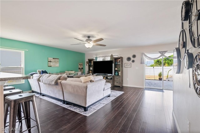 living room with dark wood finished floors, a ceiling fan, and baseboards