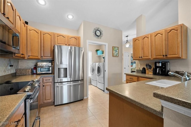 kitchen featuring light tile patterned floors, independent washer and dryer, decorative backsplash, a sink, and appliances with stainless steel finishes