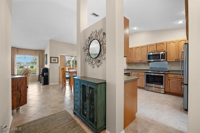 kitchen featuring light tile patterned floors, appliances with stainless steel finishes, visible vents, vaulted ceiling, and backsplash