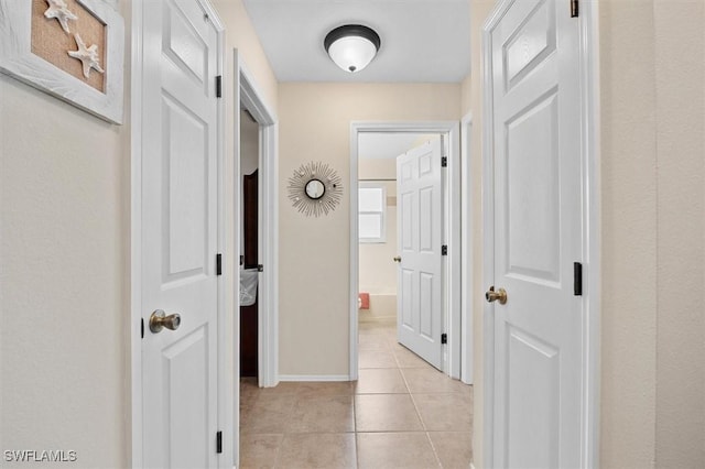 corridor with baseboards and light tile patterned flooring
