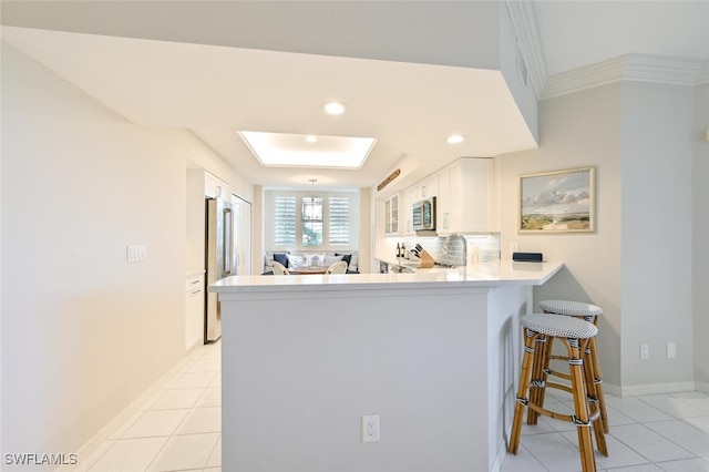 6549 Marissa Loop Unit 26, Naples, FL 34108 - kitchen featuring white cabinetry, appliances with stainless steel finishes, light tile patterned floors, and a peninsula