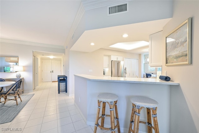 6549 Marissa Loop Unit 26, Naples, FL 34108 - kitchen featuring visible vents, light countertops, white cabinets, ornamental molding, and high end fridge