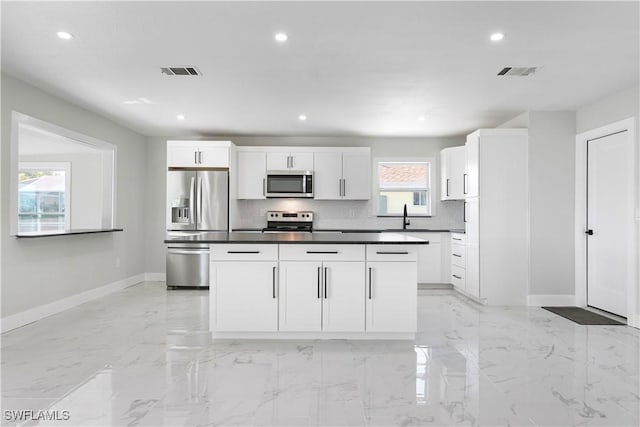 kitchen with appliances with stainless steel finishes, visible vents, tasteful backsplash, and baseboards