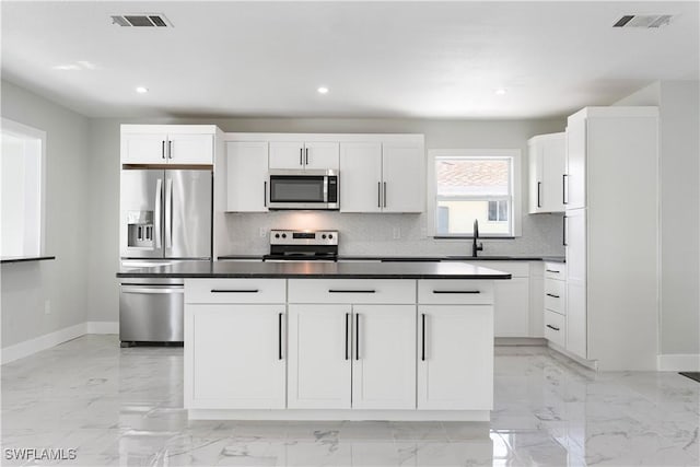 kitchen with decorative backsplash, stainless steel appliances, marble finish floor, visible vents, and baseboards