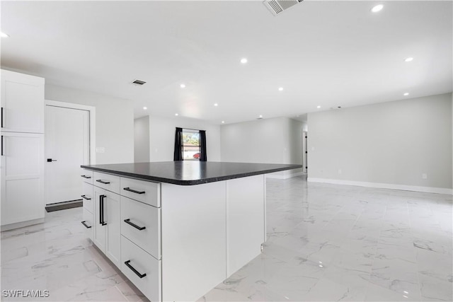 kitchen with dark countertops, marble finish floor, visible vents, and white cabinetry