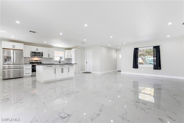 interior space featuring white cabinetry, baseboards, dark countertops, appliances with stainless steel finishes, and open floor plan