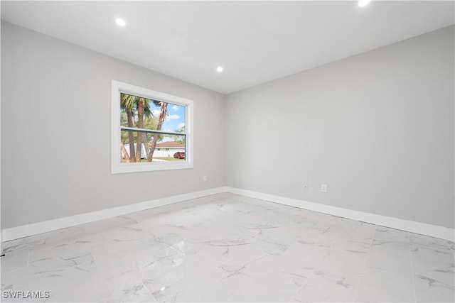 empty room featuring recessed lighting, marble finish floor, and baseboards