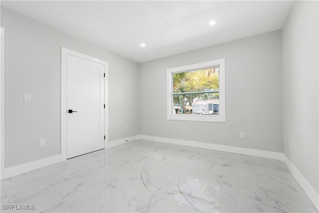 empty room featuring recessed lighting, marble finish floor, and baseboards