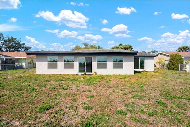 rear view of house featuring a yard, stucco siding, and fence