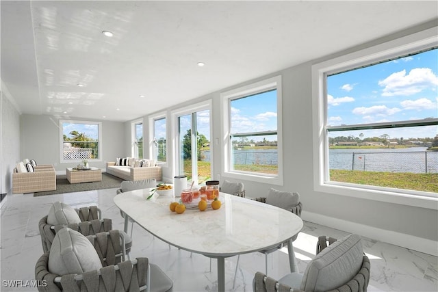 sunroom featuring a water view